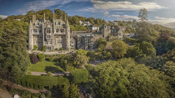 Un edificio de piedra grande e histórico con múltiples torres y un jardín bien cuidado.