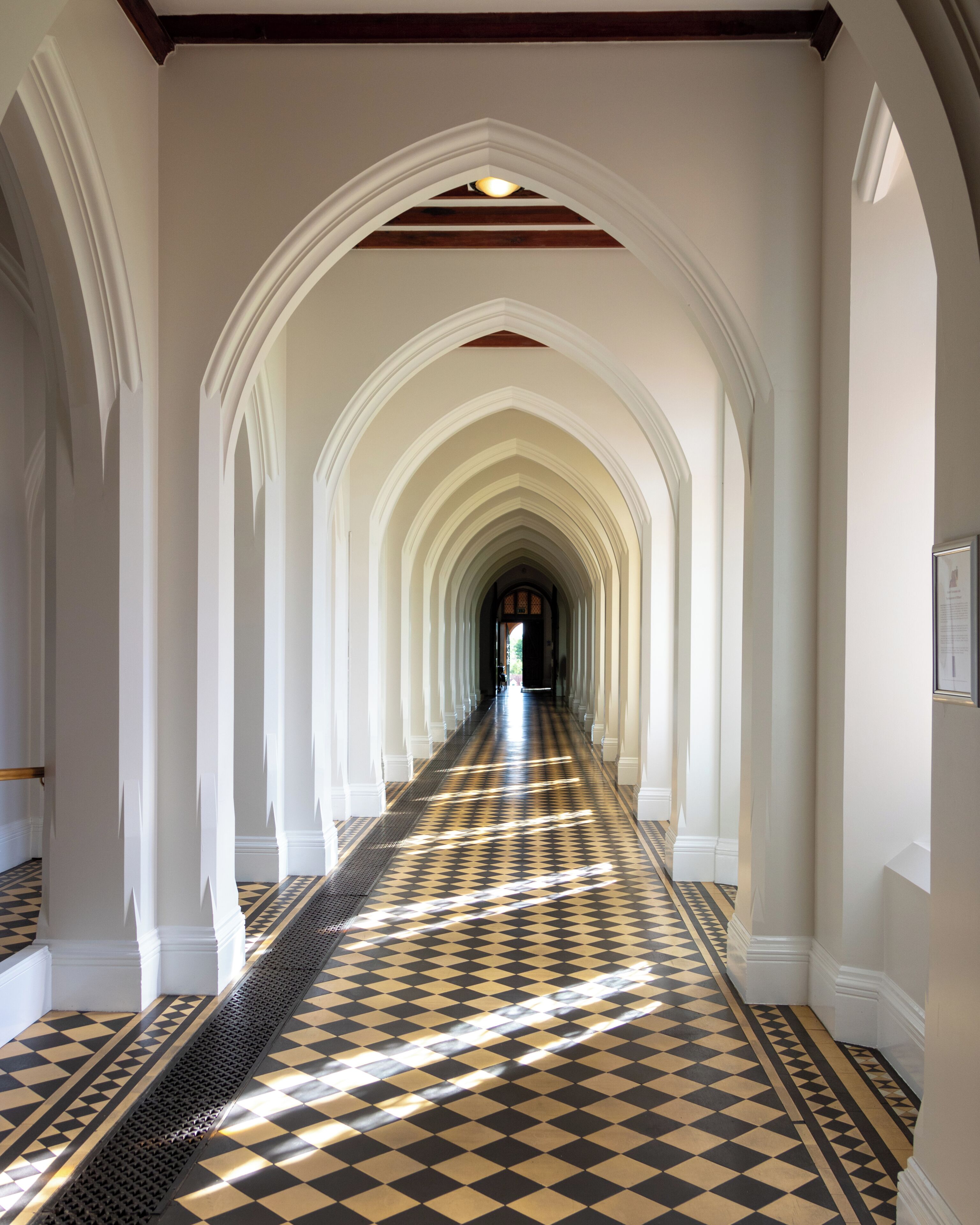 A long, narrow hallway with a checkered floor and white walls.