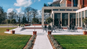 Un edificio moderno con un patio, zona de estar al aire libre y un camino que lleva a la entrada.