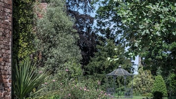 A brick pathway leading to a gazebo in a garden with various plants and flowers.