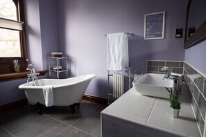 A bathroom with a freestanding bathtub, a sink, and a window with a view of trees. - Stanbrook Abbey (Worcester)