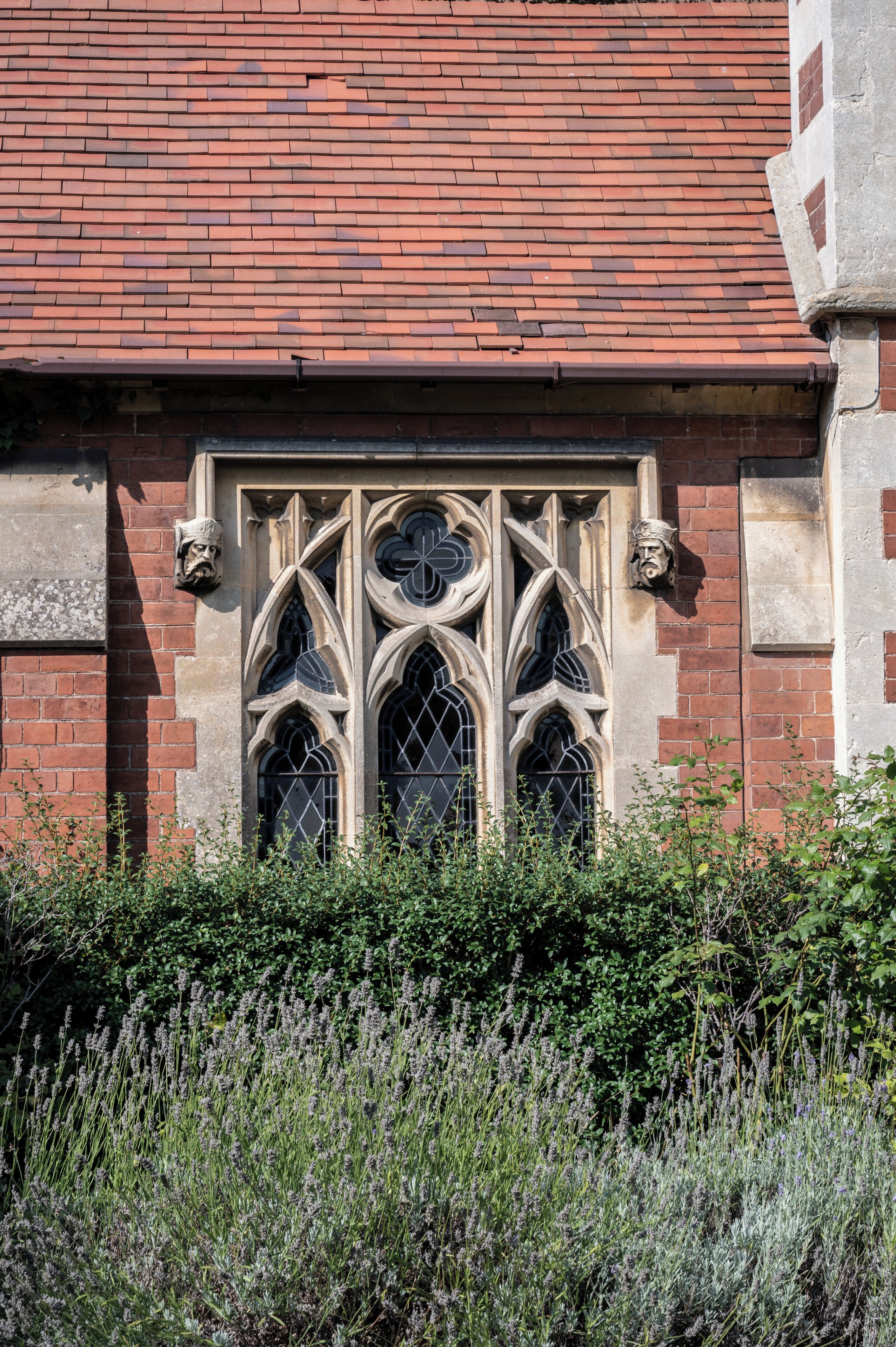 A building with a red brick facade and a window with pointed arches and intricate tracery.