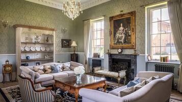 A traditional room with a fireplace, a large portrait, and classic furniture.
