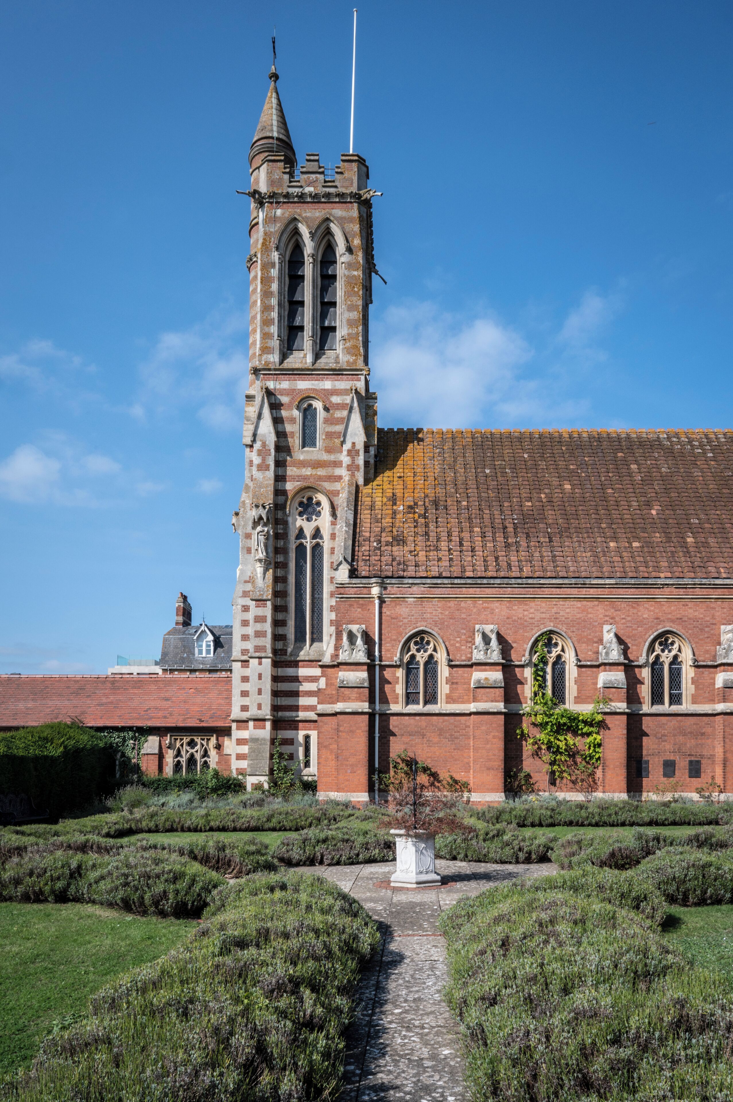 A historic building with a prominent tower, arched windows, and a paved pathway leading to it.