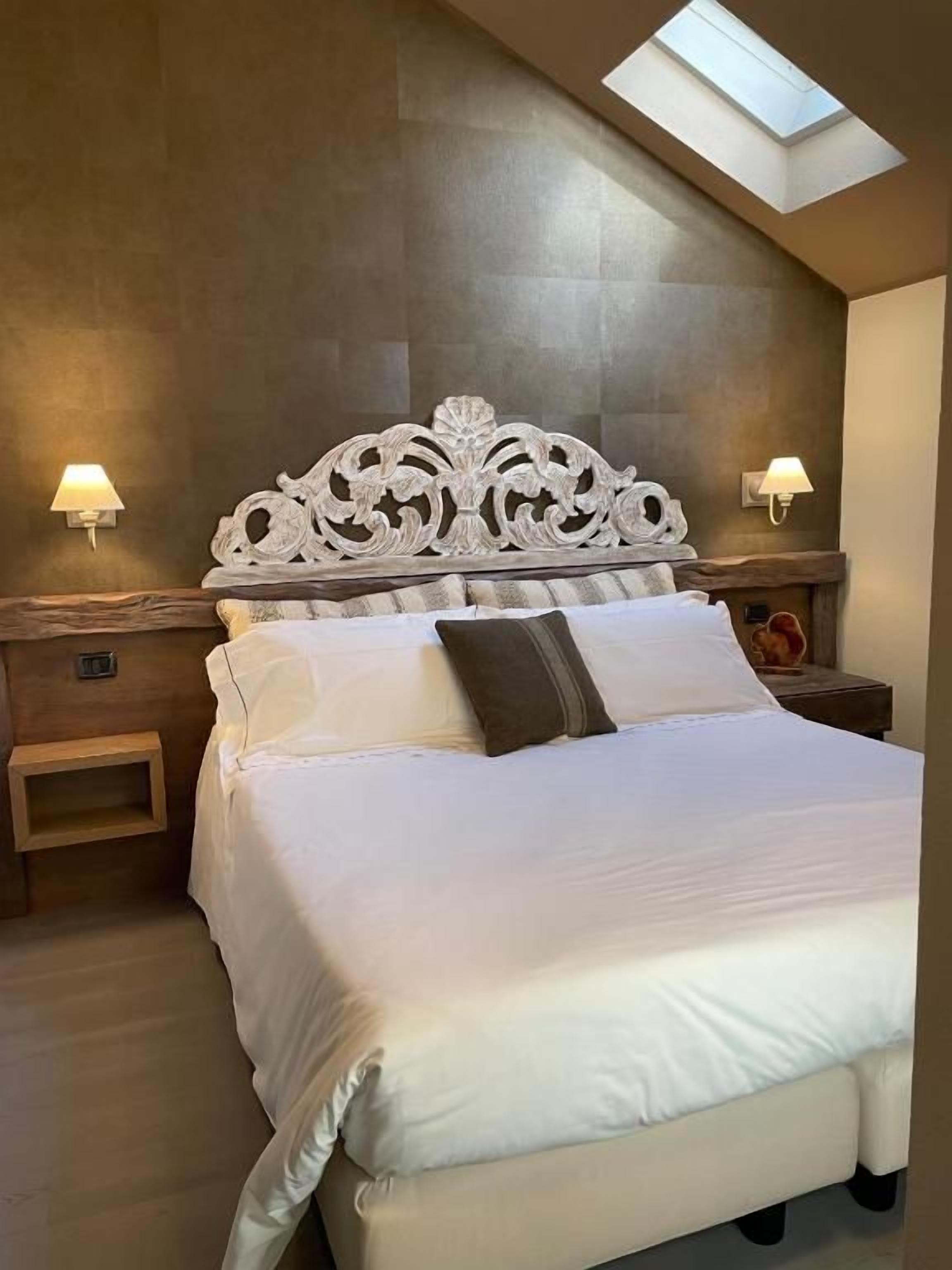 A bedroom with a large bed, a skylight, and two bedside lamps.