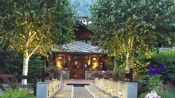 A traditional building with a tiled roof, surrounded by lush greenery and a paved pathway leading to the entrance. - Residence Courmaison (Pre-Saint-Didier)
