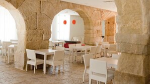 Un restaurant doté d’arches en pierre, de mobilier blanc et d’un aménagement intérieur moderne.