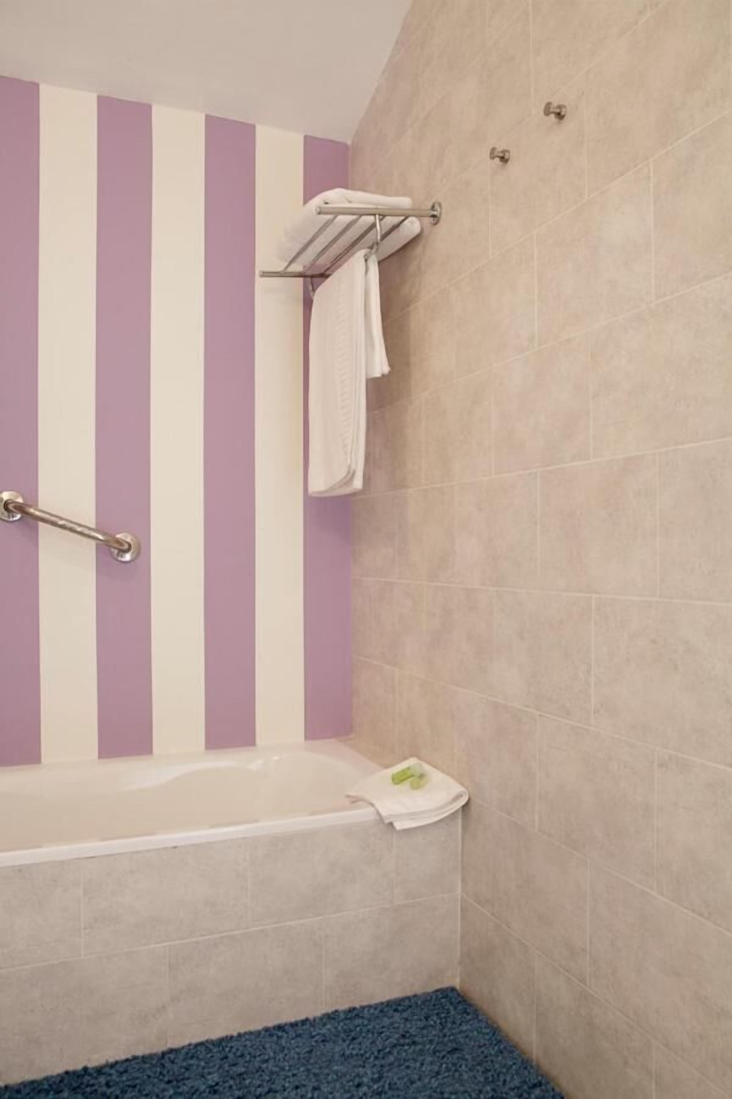 Ein Badezimmer mit einer Badewanne, einer Handstange und einem Handtuchhalter.