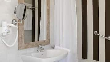 A bathroom with a white sink, a mirror with a wooden frame, a towel rack, a shower curtain, and a grab bar.