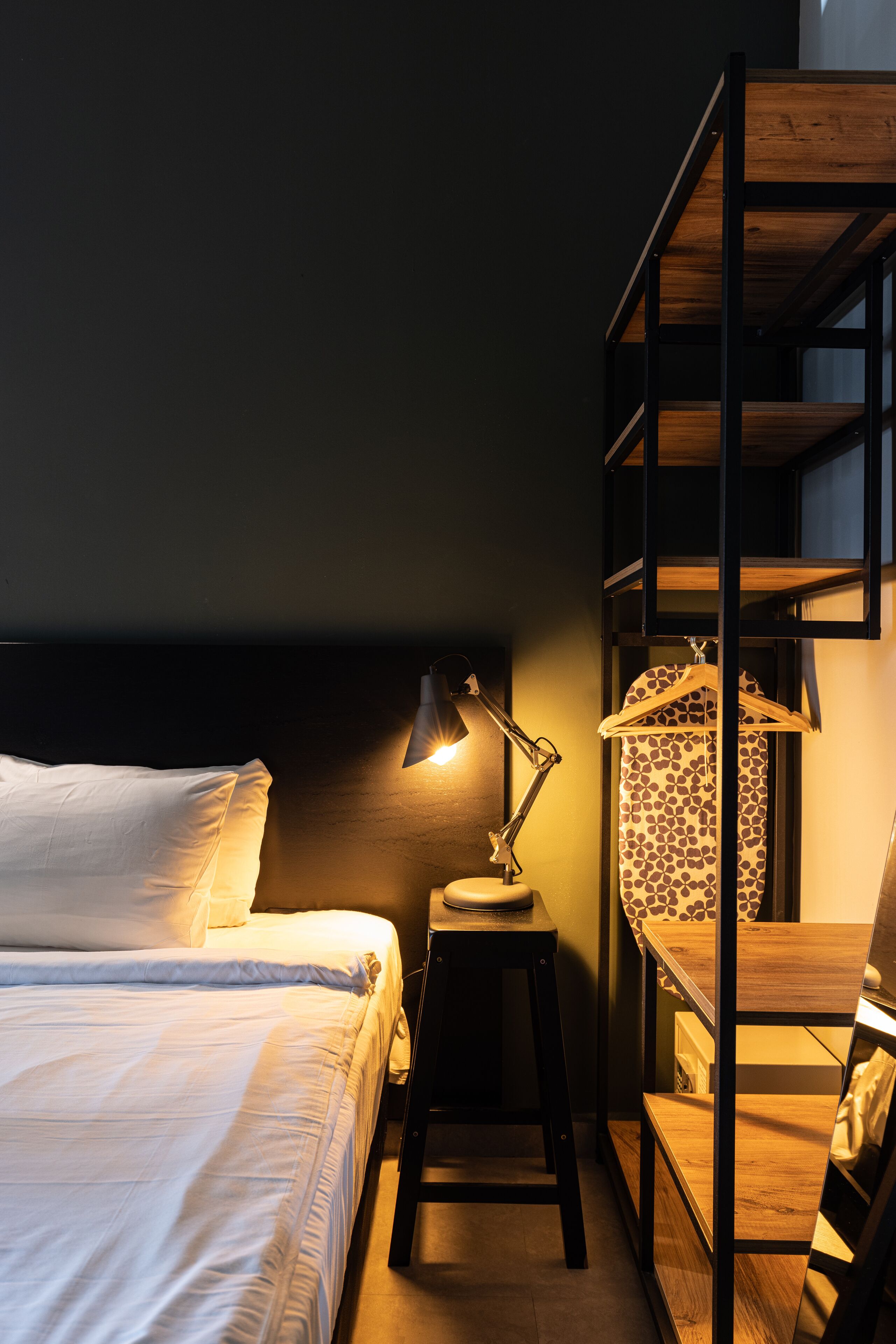 A bunk bed with a wooden frame, a bedside table with a lamp, and a patterned curtain.