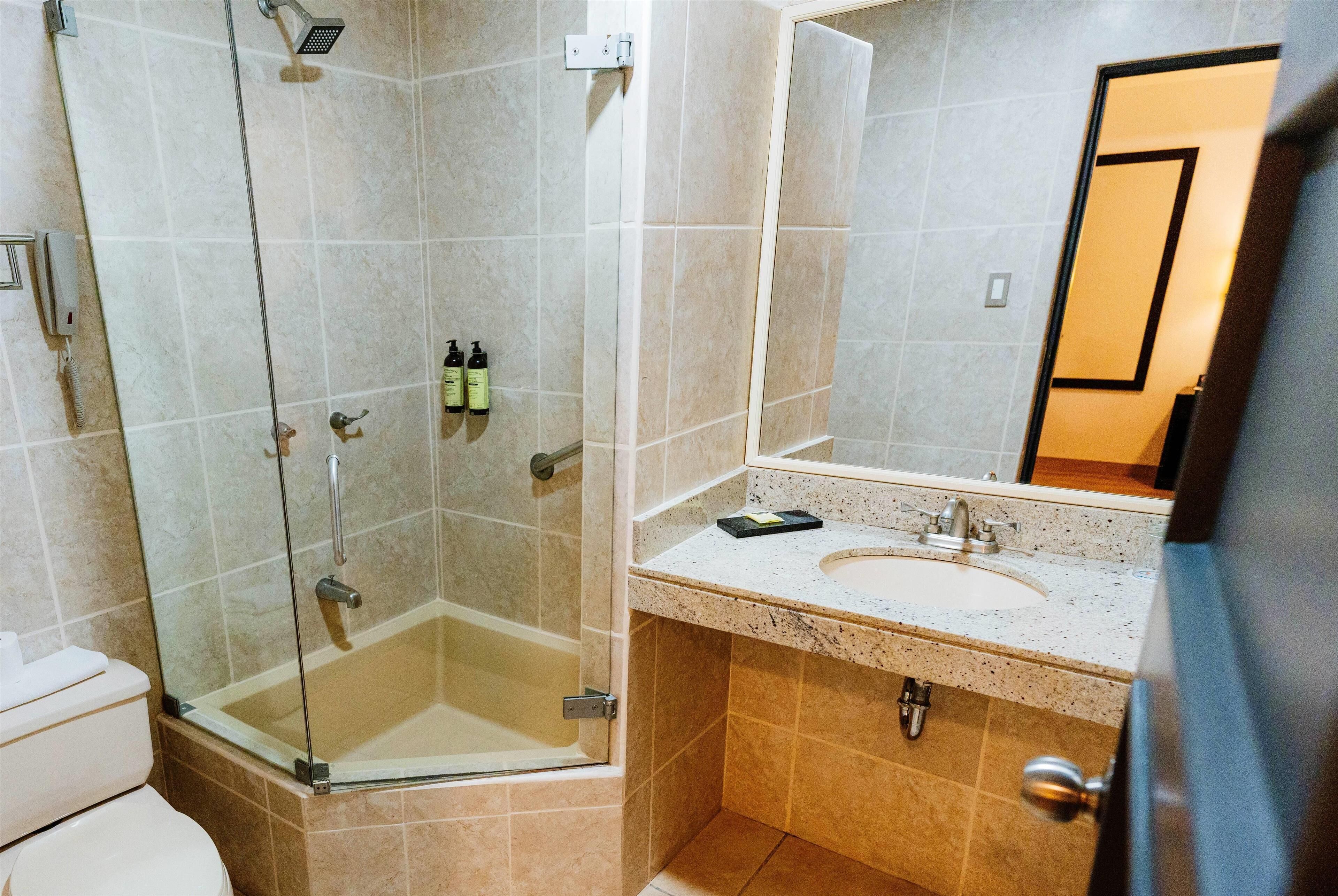 Un baño con ducha de vidrio, lavamanos e inodoro.
