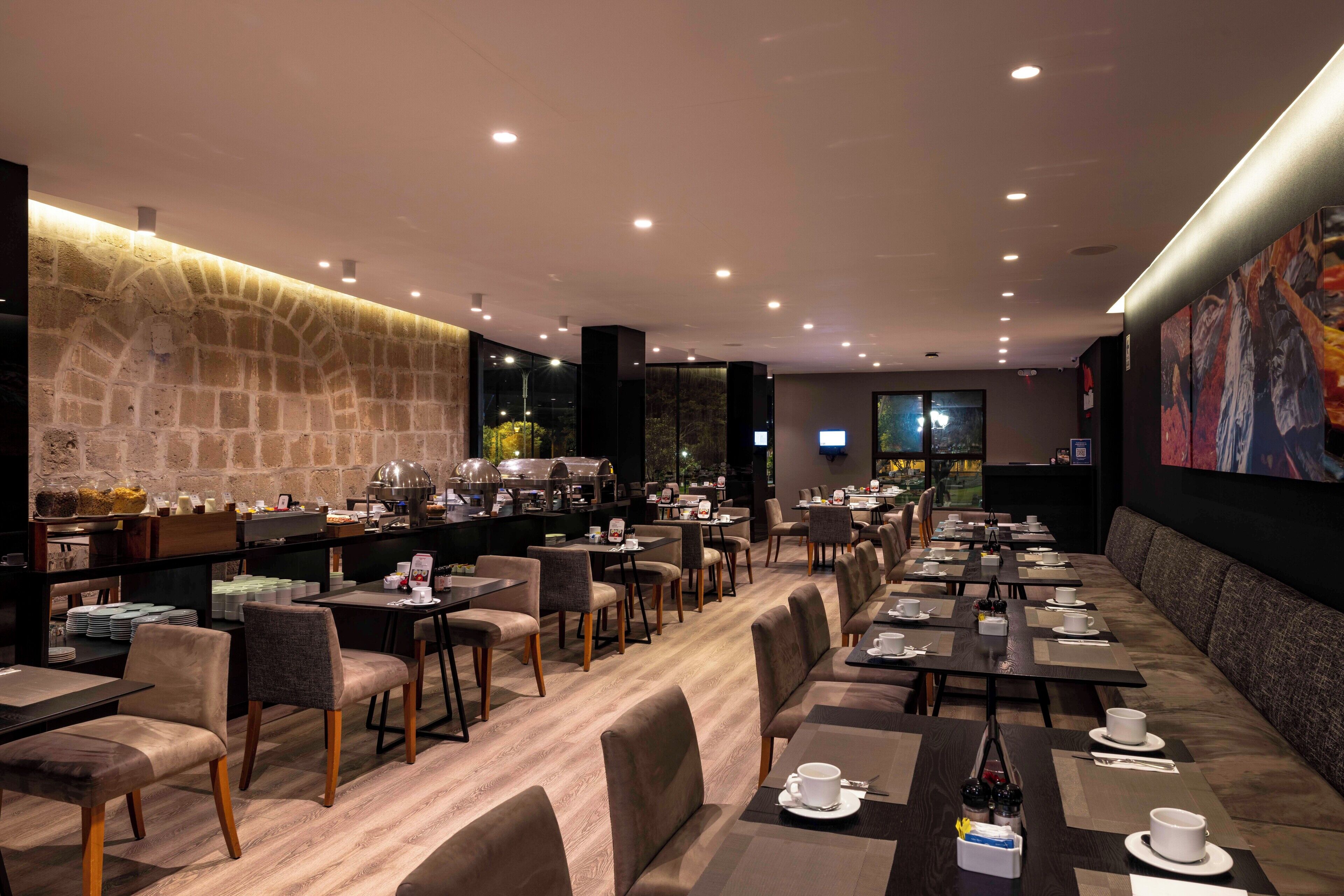 Un restaurante moderno con pared de piedra, varias mesas y sillas dispuestas para comer.