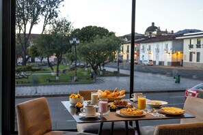 A breakfast table with various dishes and beverages, a view of a street with buildings and trees, and a car parked on the side. - Wyndham Costa del Sol Cajamarca (Cajamarca)