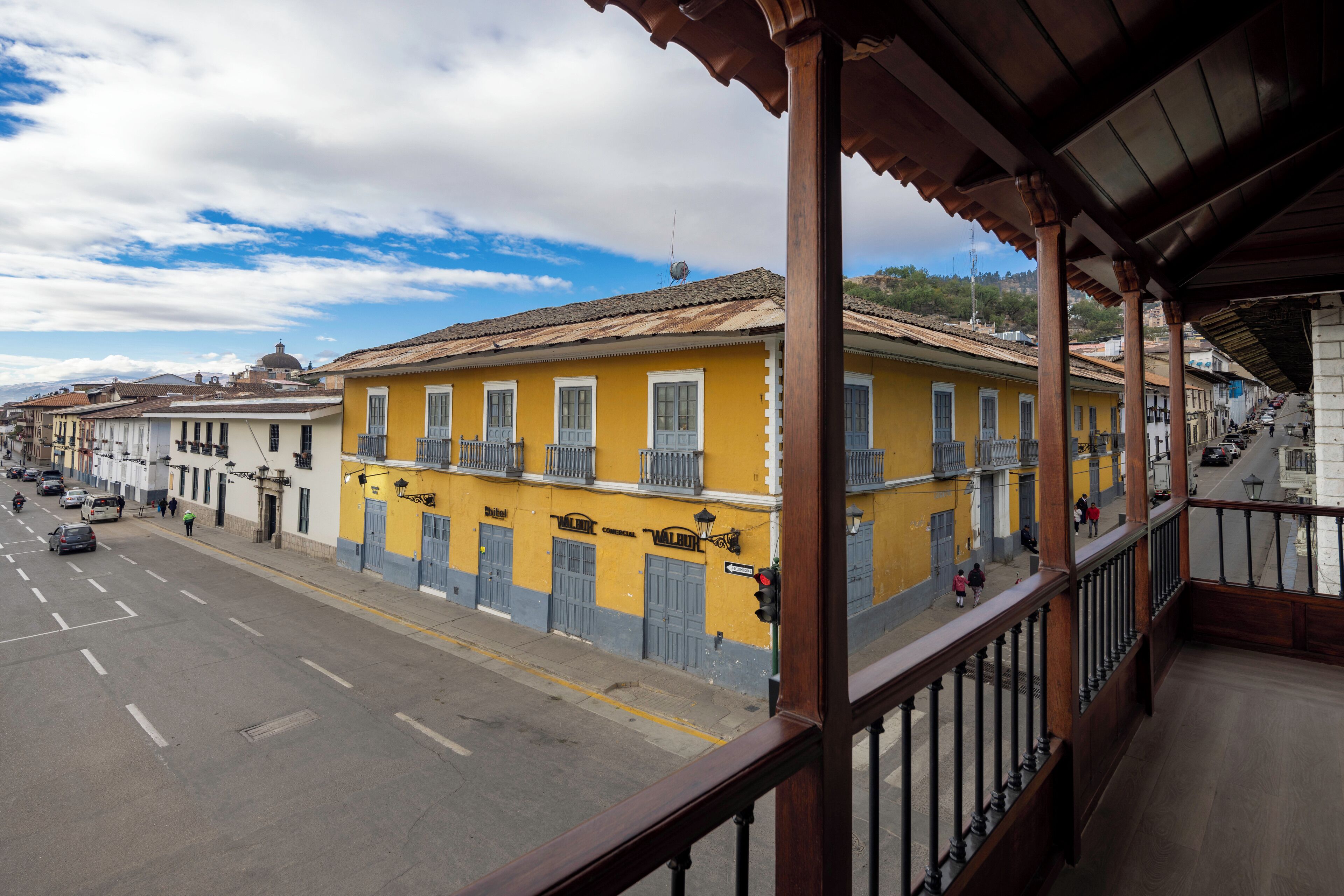 A yellow building with balconies and a street in front.