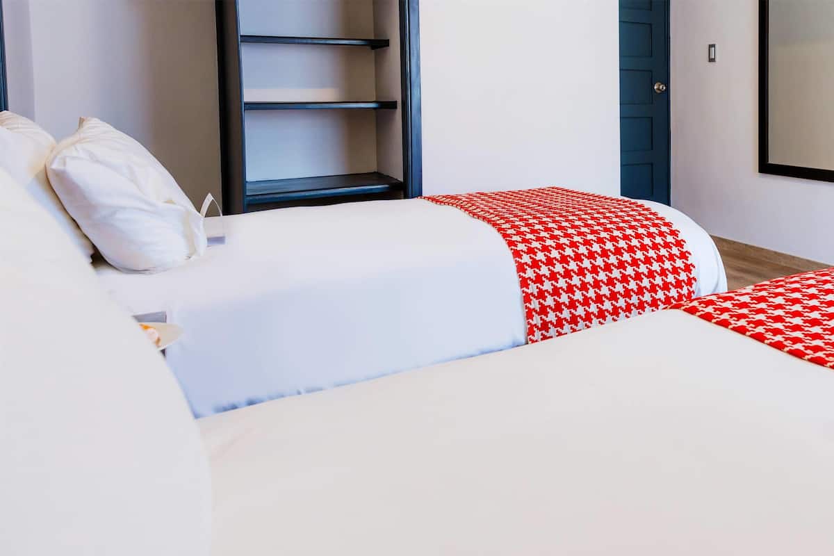 A hotel room with two beds, a wardrobe, and a door.