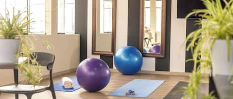Ett rum med träningsutrustning, en stol, en yogamatta och en våg.