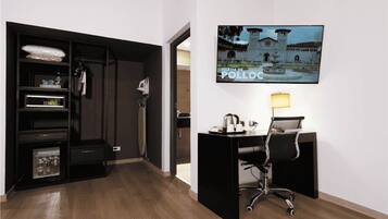 Habitación de hotel con escritorio, silla, televisión montada en la pared y minibar.