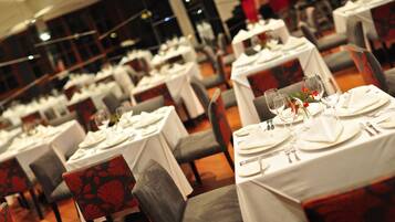 Un restaurante con varias mesas preparadas para comer, cada una con manteles blancos y cubiertos ordenados.