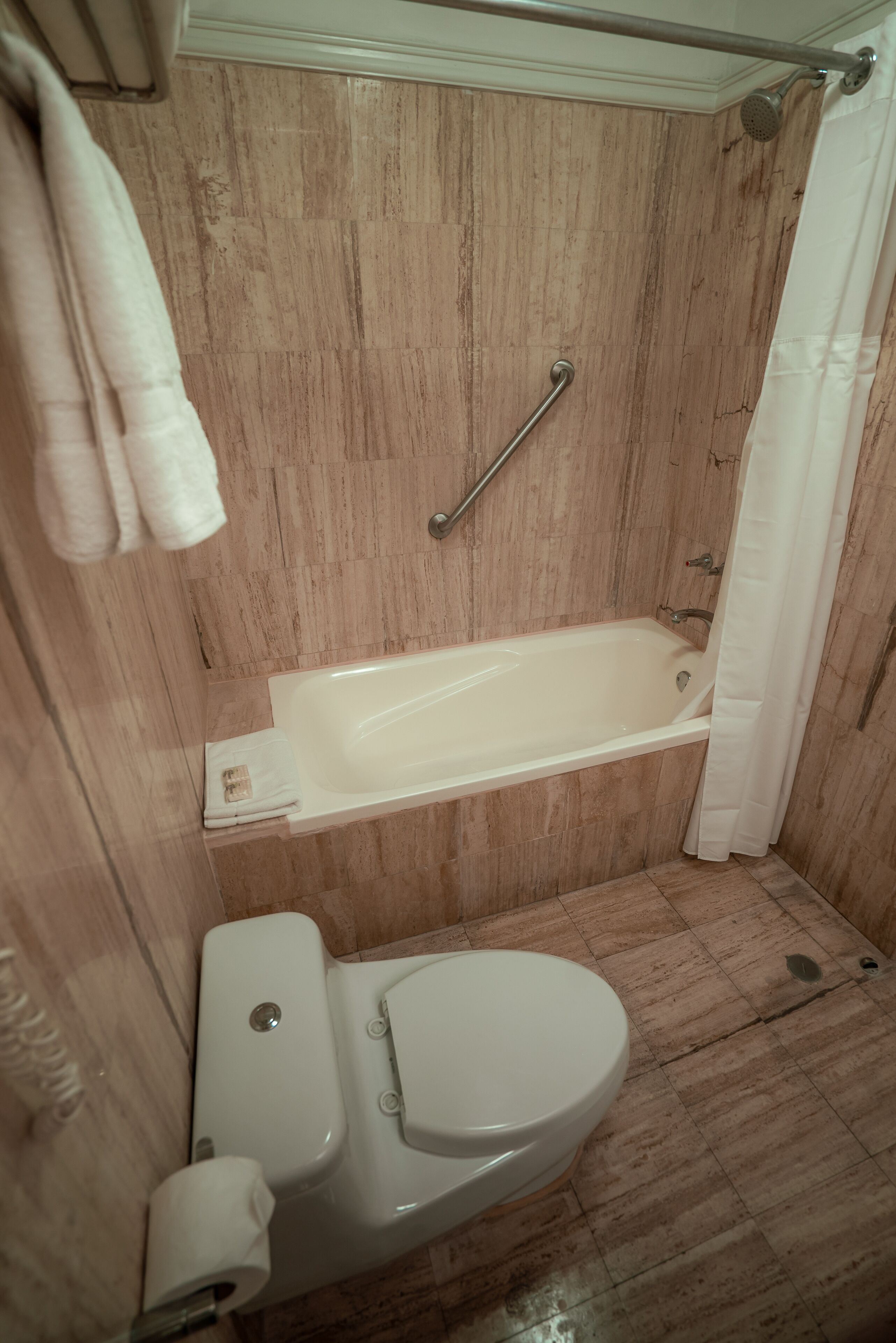 A bathroom with a bathtub, toilet, and shower curtain.
