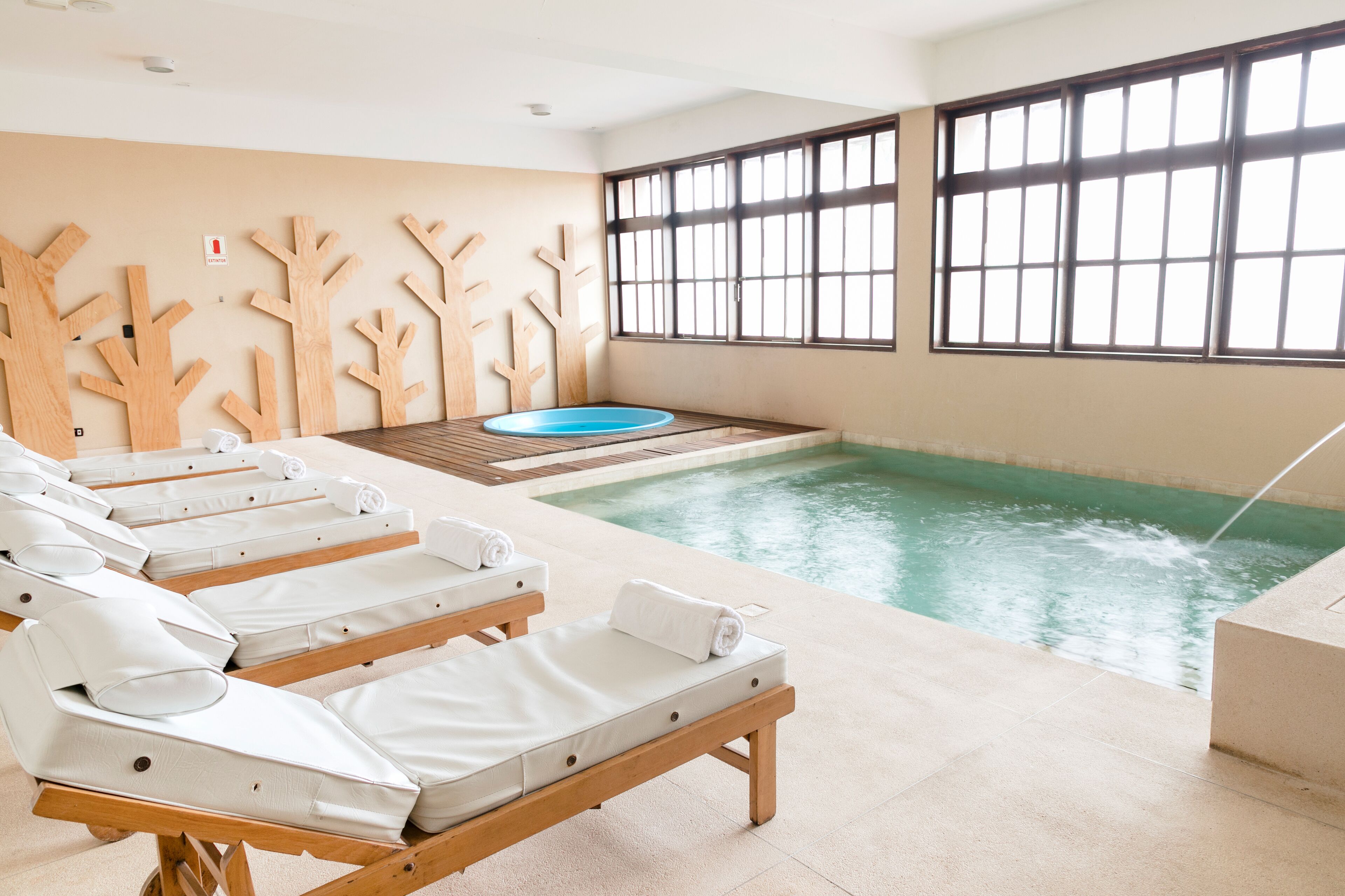 Ein Wellnessbereich mit Pool, Holzpaneelen und Liegestühlen.