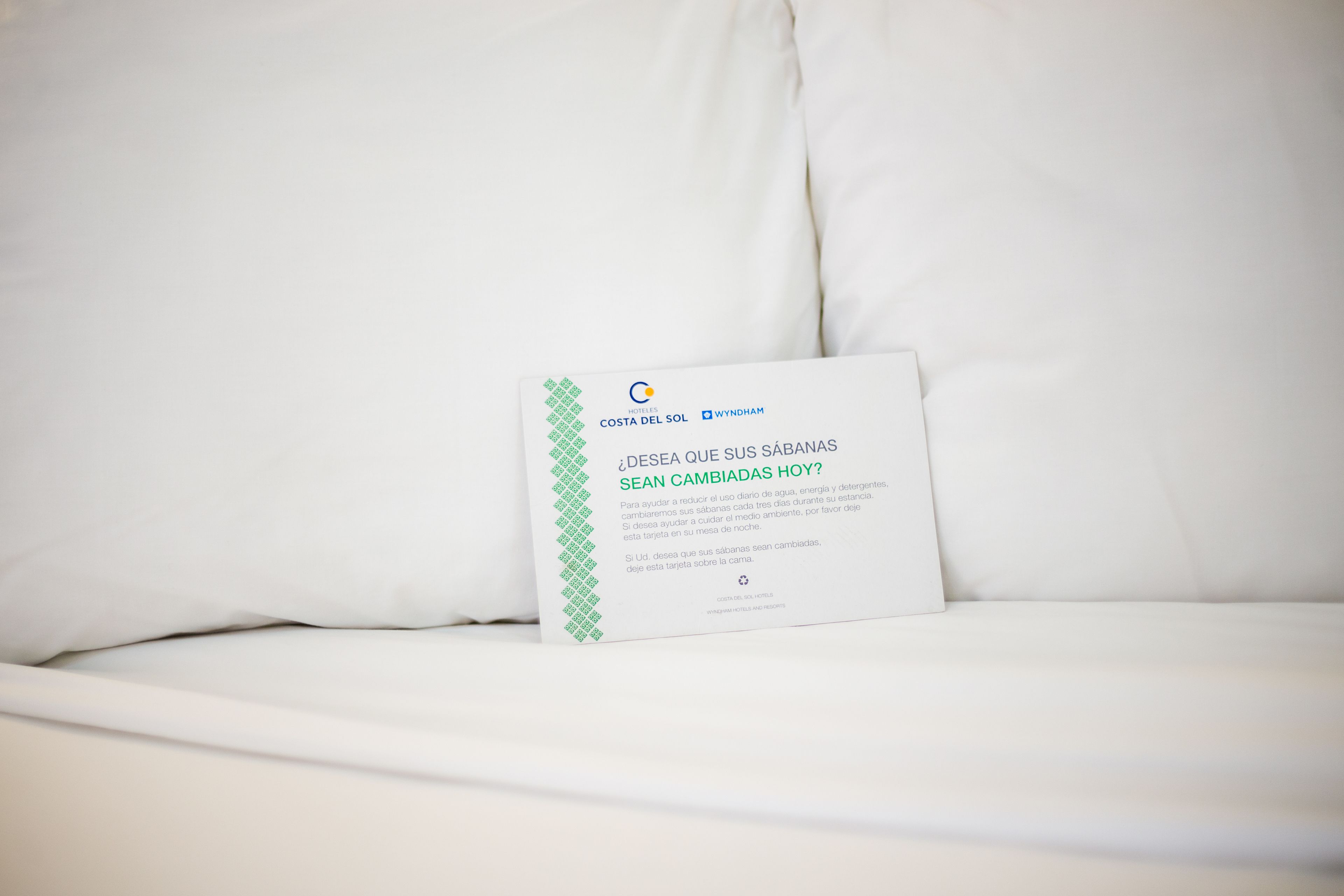 Una cama blanca con una tarjeta encima.