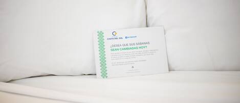 A white bed with a card on it.