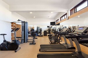 Un gimnasio moderno con diversos equipos de ejercicio, incluyendo cintas de correr y máquinas de pesas.
