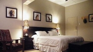 Quarto com cama, mesas de cabeceira, uma cadeira e obras de arte na parede.