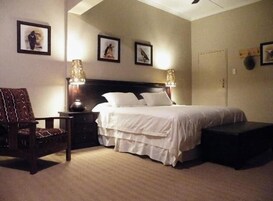 Un dormitorio con cama, mesitas de noche, una silla y decoración en la pared.