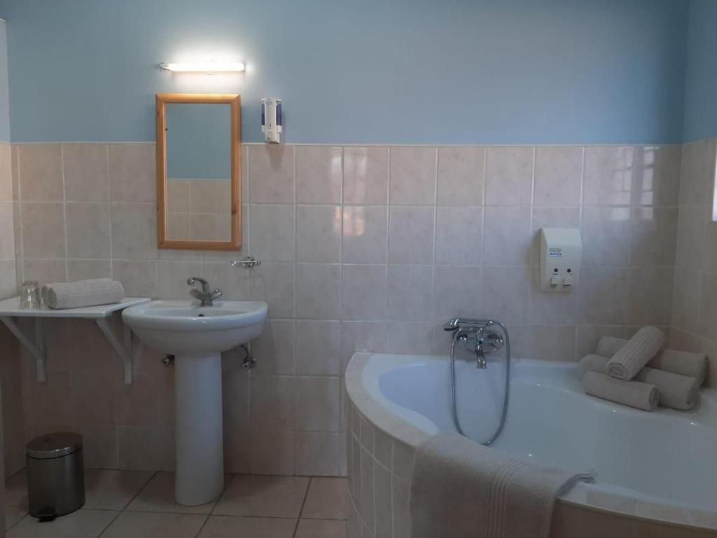 A bathroom with a sink, mirror, and bathtub.