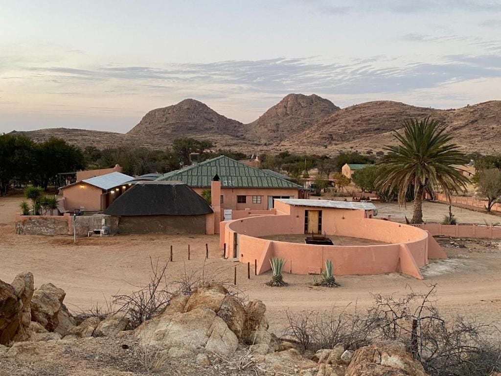 A desert landscape with a building featuring a curved structure and a green roof.
