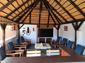 An outdoor seating area with wooden furniture and a thatched roof. - Goibib Mountain Lodge (Grunau)