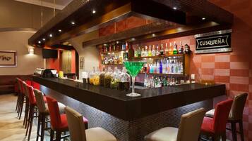 A bar area with a counter, stools, and a variety of bottles.
