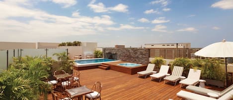 Una terraza en la azotea con piscina, sillas de descanso y zona de comedor.