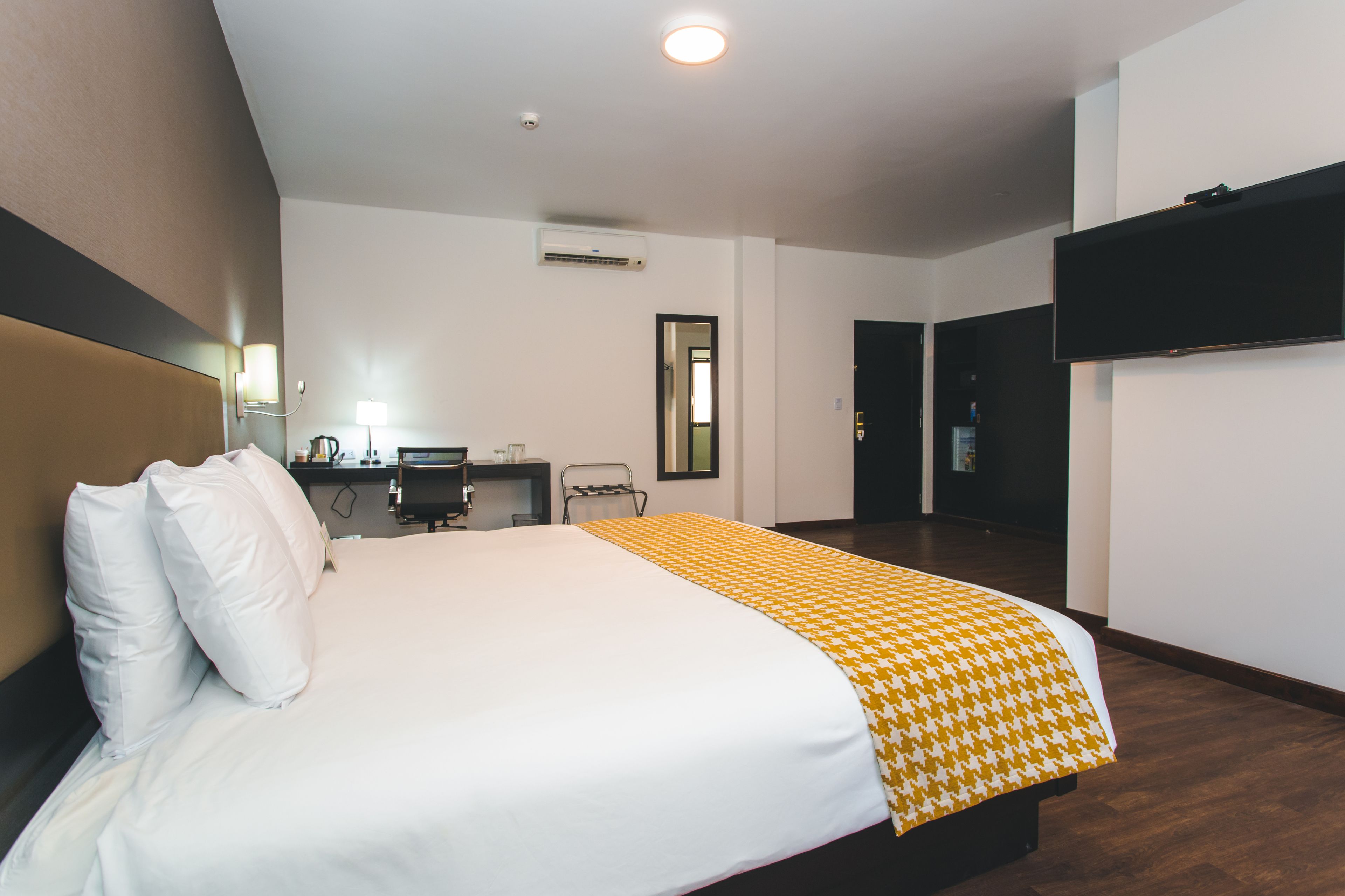Een hotelkamer met een groot bed, een bureau, een stoel en een flatscreen televisie aan de muur.