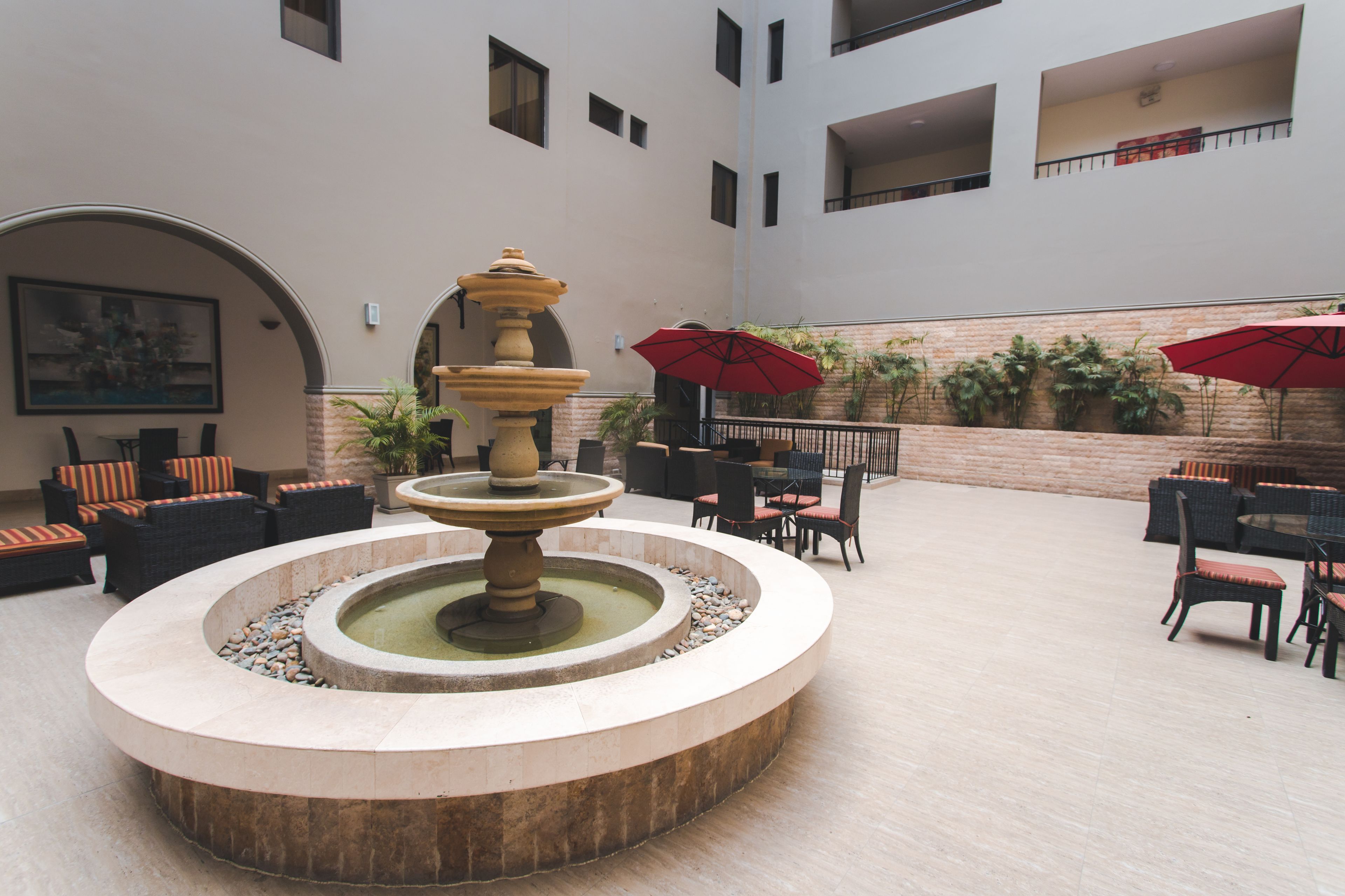 Un patio con una fuente circular, mobiliario exterior y plantas en macetas.