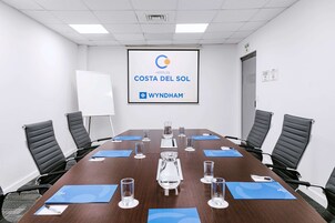 Un salón de conferencias con una mesa larga, sillas negras y una pantalla que muestra el logotipo de Costa del Sol Wyndham.