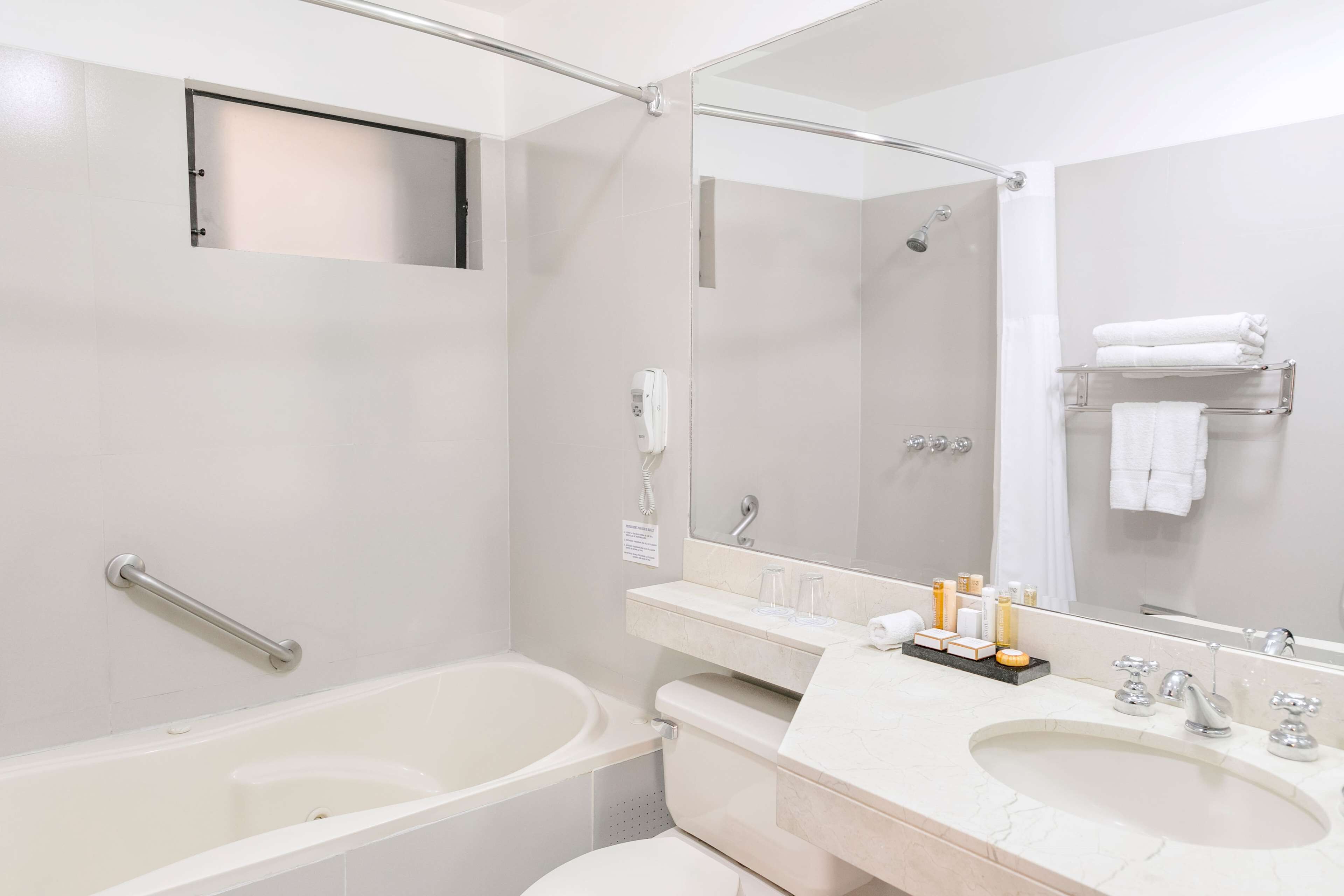 Un baño moderno con bañera, lavamanos, tocador y un espejo grande.