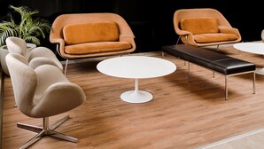 A modern interior with a black and white color scheme, featuring a chandelier, leather armchairs, a round white table, and a bench.
