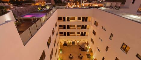 A multi-level hotel courtyard with a pool, outdoor seating, and a central fountain.