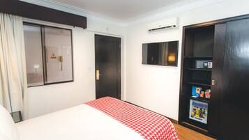 Quarto de hotel com cama, guarda-roupa, televisão e minibar.