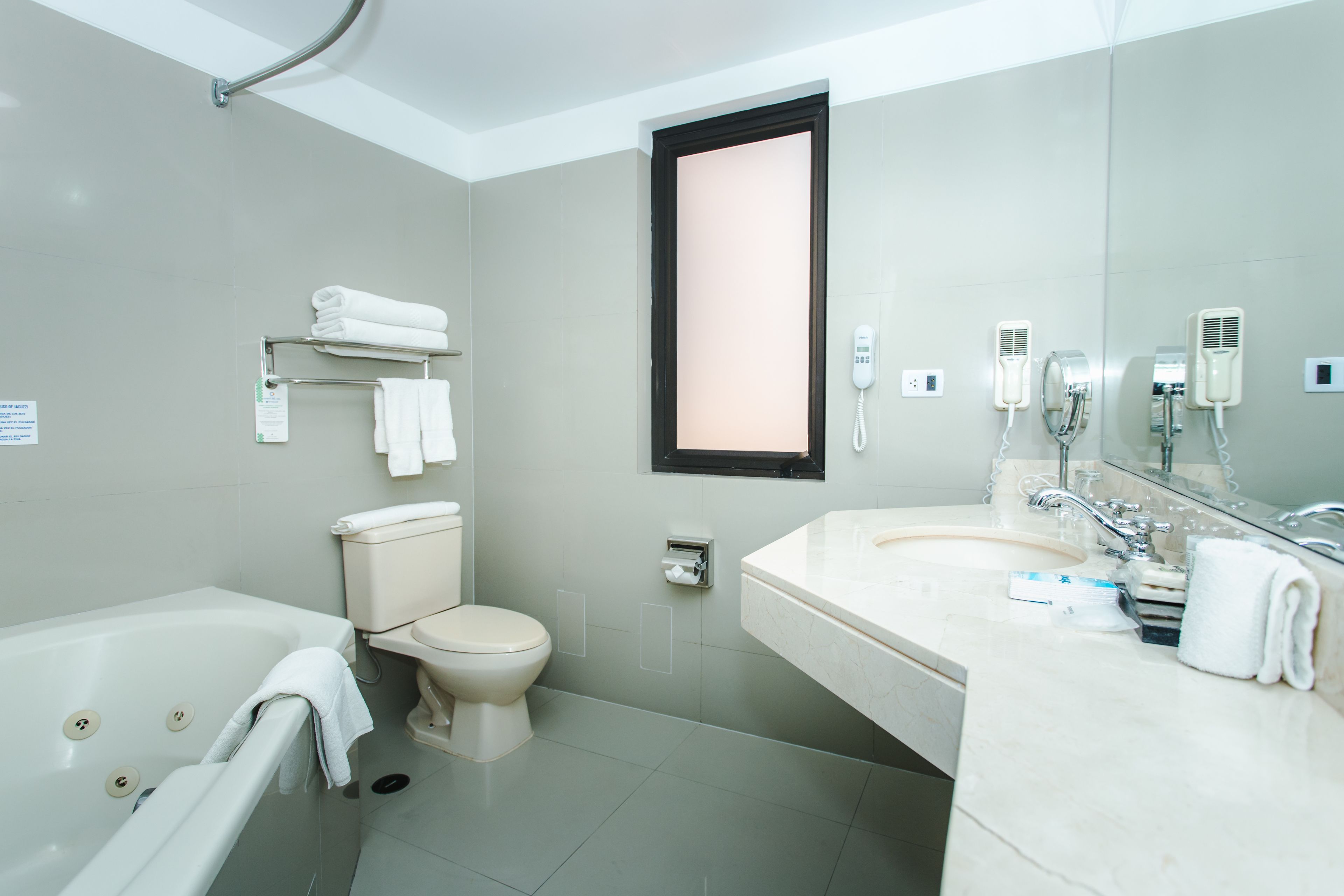 Un baño moderno con bañera, inodoro y un espejo grande sobre el lavamanos.