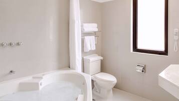 A modern bathroom with a bathtub, toilet, and a window.