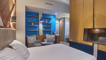 Quarto de hotel com cama, área de estar e televisão.