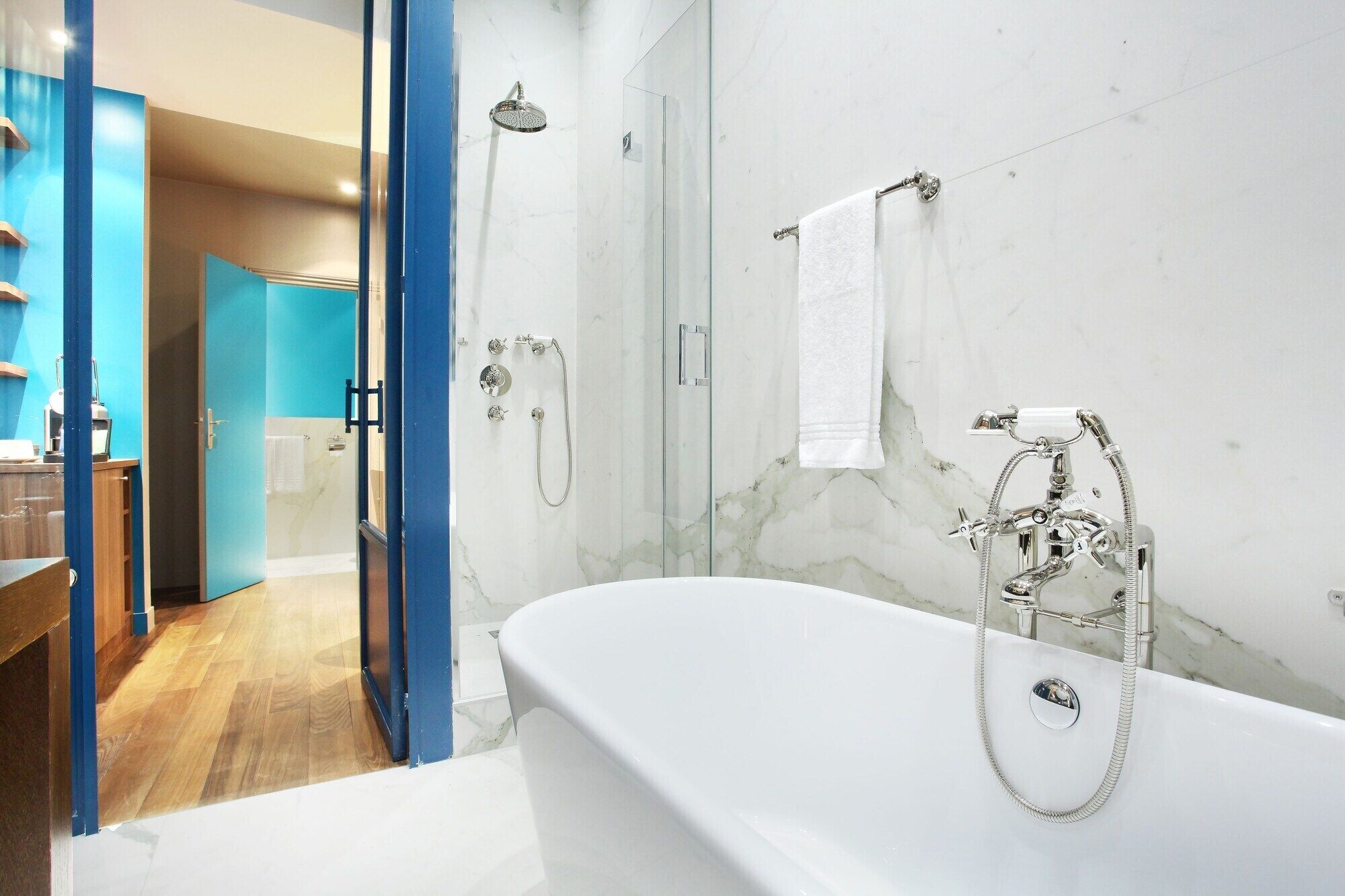 A modern bathroom with a freestanding bathtub, a glass-enclosed shower, and a marble wall.
