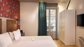 A hotel room with a bed, a wardrobe, a television, and a window with curtains.