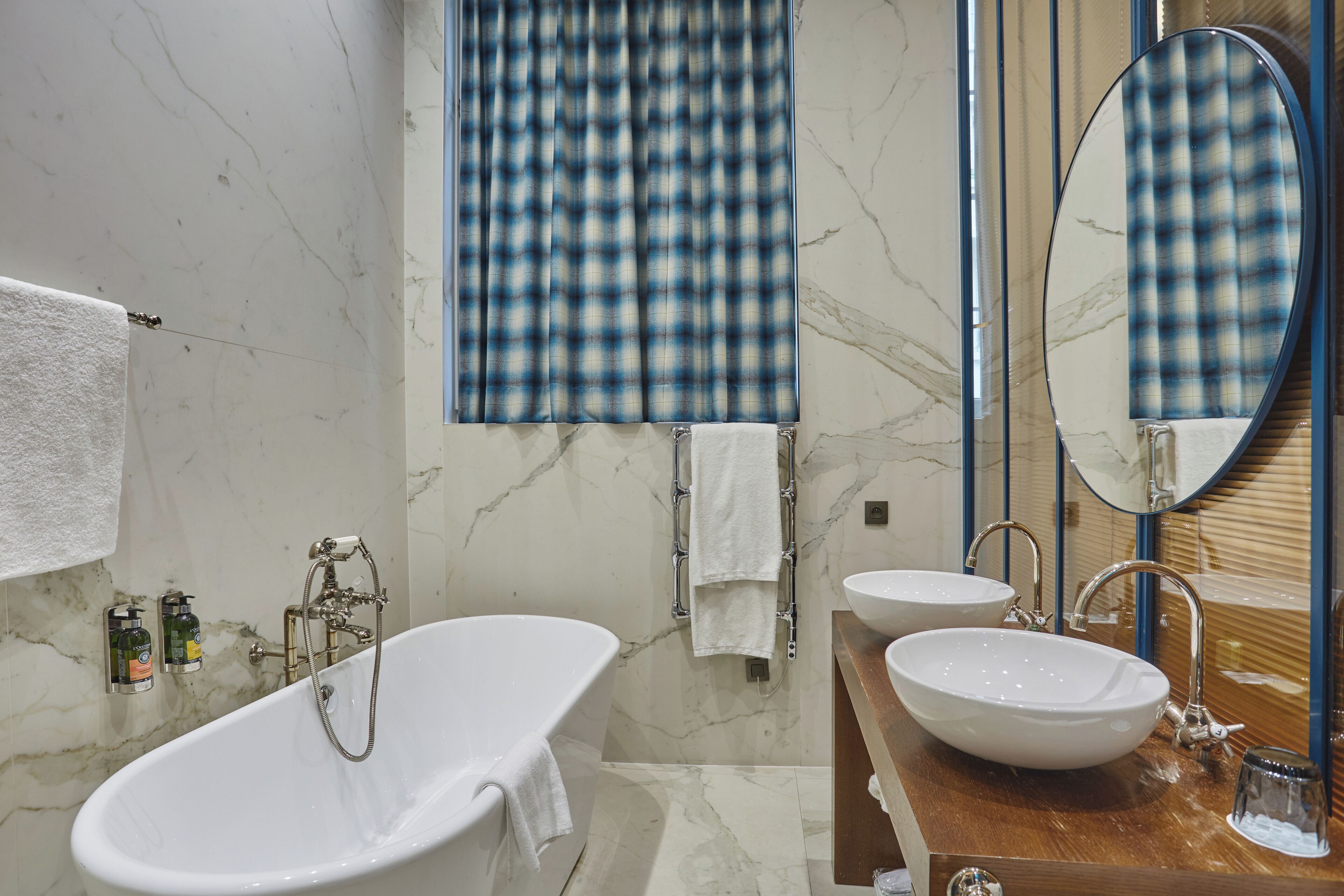 Une salle de bain avec une baignoire sur pieds, deux lavabos, un miroir et un porte-serviettes.