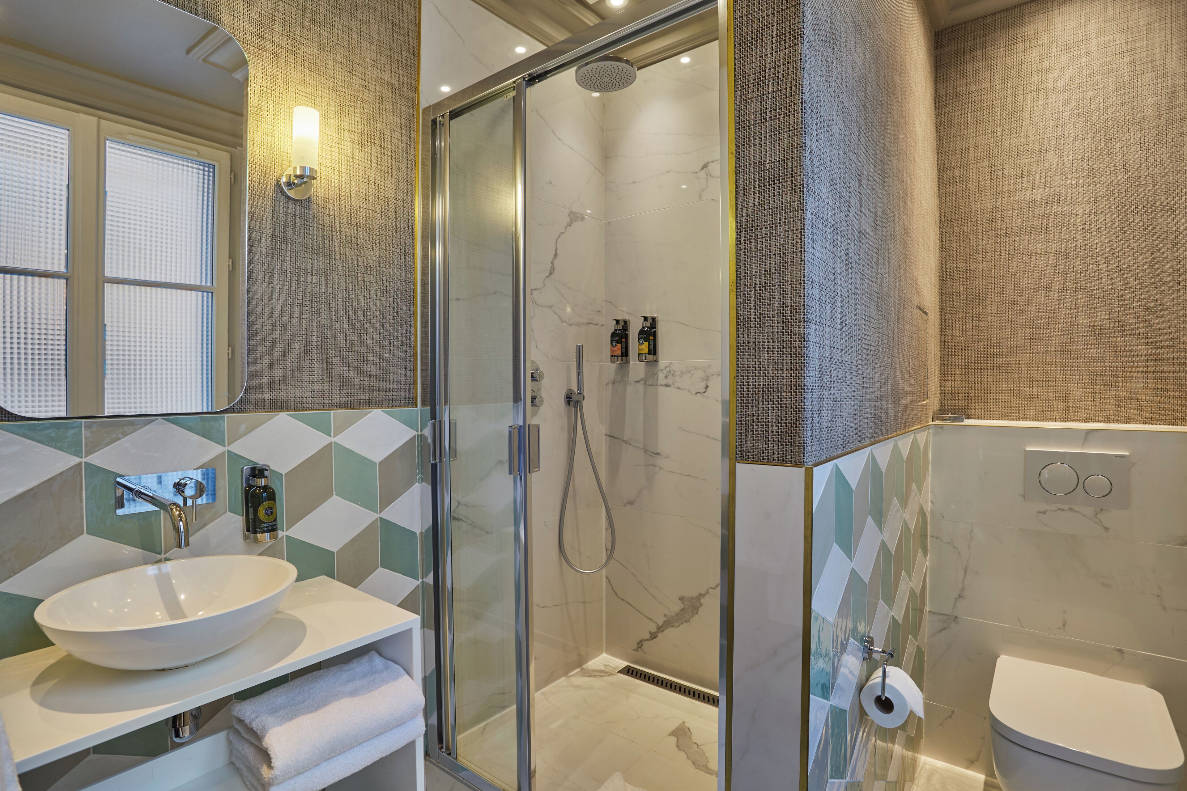 Une salle de bain moderne avec une douche à parois de verre, un lavabo blanc et des toilettes.