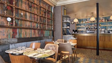 A restaurant interior with a bar area, seating, and a decorative wall with pipes.
