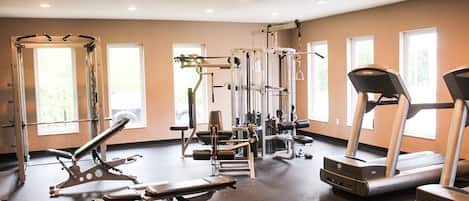 A gym with various exercise equipment, large windows, and a treadmill.
